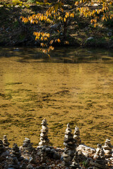 Stone Cairns beside Clear Autumn River Surface