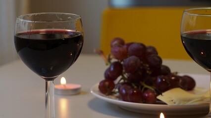 Romantic couple enjoying dinner at home, concept love, relationship and romantic, happy couple celebrating and making cheers with glasses of red wine. girl eats grapes and cheese, Valentine's Day
