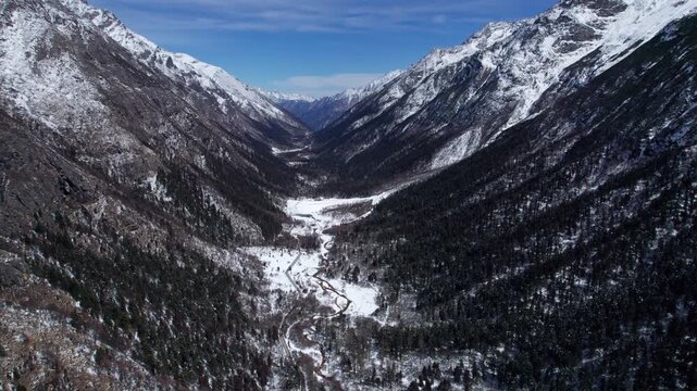Drone view of snow covered mountains and forests in Bipeng Valley in Sichuan, China in sunny winter day, high angle view of beautiful winter landscape. 4k real time footage, travel concept