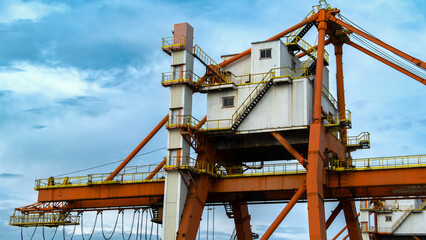 Detailed close up of the cabin and structural components of a massive orange and white gantry crane used for handling cargo in a port