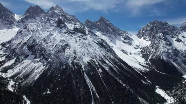 Drone view of snow covered mountains and forests in Bipeng Valley in Sichuan, China in sunny winter day, high angle view of beautiful winter landscape. 4k real time footage, travel concept