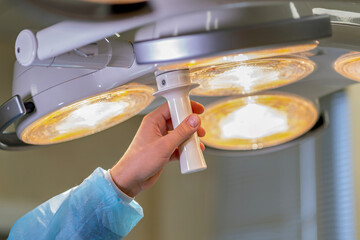 A person holding a light fixture in an operating room