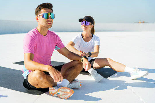 Two friends relax and stretch on yoga mats outdoors