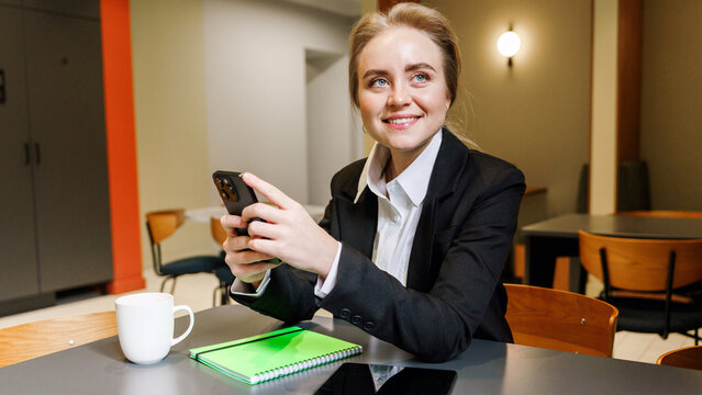 Business professional smiles while using smartphone in cafe - Powered by Adobe
