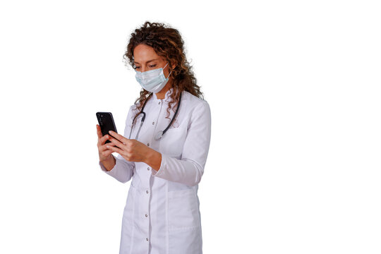 Female doctor or nurse in lab coat and face mask using smartphone for telehealth, medical consultation, or communication