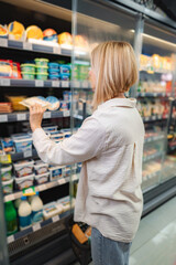 Woman shopping for cheese in supermarket dairy section