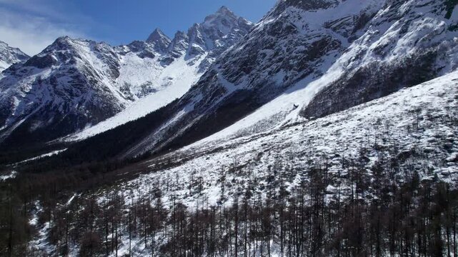 Drone view of snow covered mountains and forests in Bipeng Valley in Sichuan, China in sunny winter day, high angle view of beautiful winter landscape. 4k real time footage, travel concept
