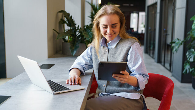Woman smiles while using tablet in modern workspace