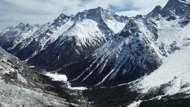 Drone view of snow covered mountains and forests in Bipeng Valley in Sichuan, China in sunny winter day, high angle view of beautiful winter landscape. 4k real time footage, travel concept