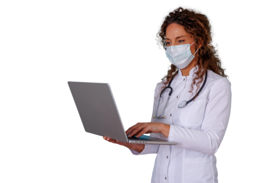 Female doctor in medical mask using laptop, delivering telehealth consultation or managing patient data - Powered by Adobe