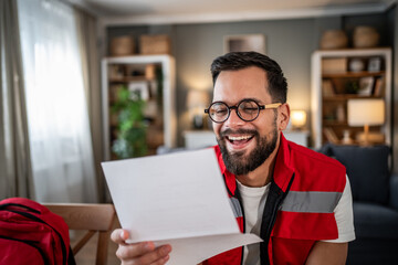 Paramedic man reading document and laughing with relief