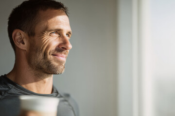 young man with gentle smile takes moment to relax between workout sets enjoying cup of coffee