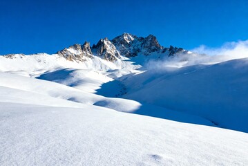 Fototapeta premium Snowy winter mountain landscape with bright blue sky, perfect nature background for travel, winter scenery, outdoor adventure and cold season visuals.