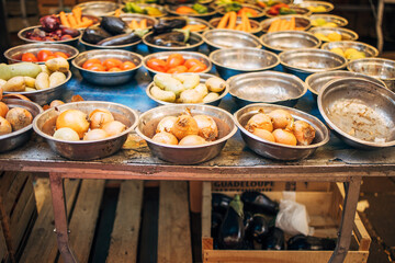 Various fresh vegetables, including onions and tomatoes, displayed on a market stall