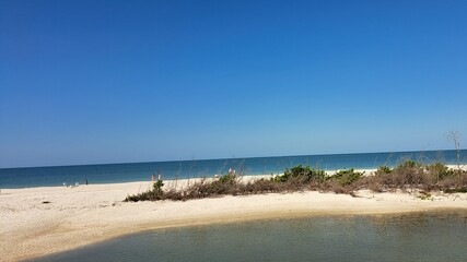 Sunny day at pristine white sand beach with blue ocean and clear sky