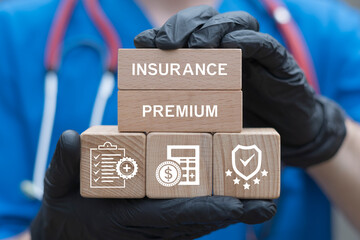 Doctor holding blocks with icons sees the inscription INSURANCE PREMIUM. Health insurance premium medicine service concept. Healthcare medical assurance help money premium healthy web technology.