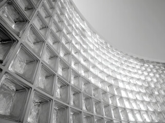 Obraz premium Black and white photograph of curved wall made from glass blocks, showcasing modern architectural design with light reflections