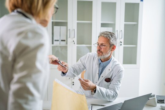Doctors collaborating exchanging medical records in clinic office - Powered by Adobe