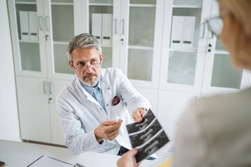 Fototapeta premium Doctor discussing medical diagnosis with patient showing ultrasound results in clinic