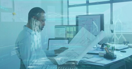 Examining architect in light-blue shirt and glasses, reviewing blueprints at office with monitors