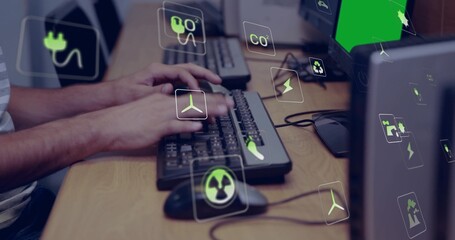 Typing man wearing short-sleeve shirt at office desk, with keyboards, mice and green UI