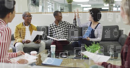 High-fiving colleagues exchanging ideas in modern office lounge, with glass table and icon overlay