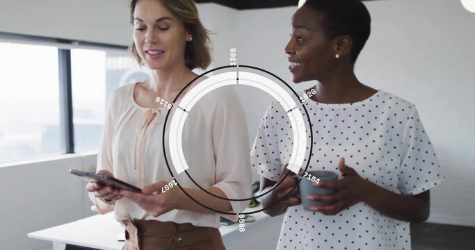 Holding tablet and gray mug, two women wearing blouses discussing data near window with HUD overlay