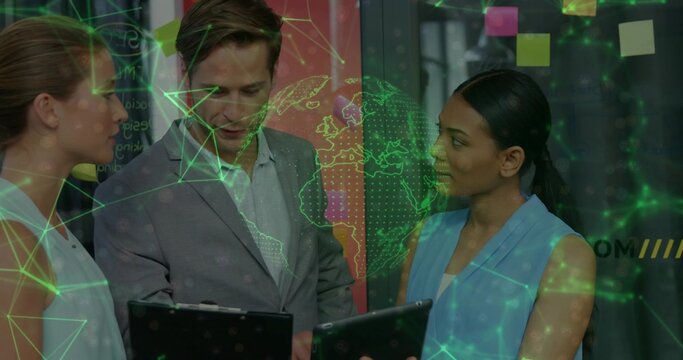 Reviewing three-person team checking tablets and clipboard in office wearing blazers with green map - Powered by Adobe