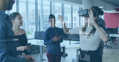Gesturing female wearing light top and dark skirt using VR headset at open-plan office, copy space
