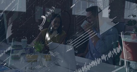 Collaborating two colleagues in business shirts analyzing laptop charts at office desk with plant