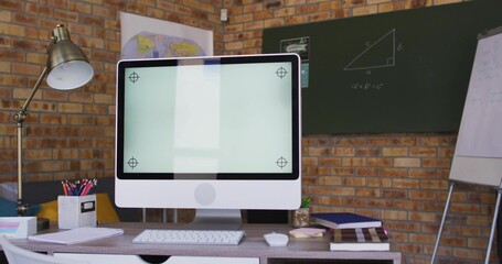 Displaying white all-in-one monitor with stand on desk in study, with keyboard, lamp, chalkboard