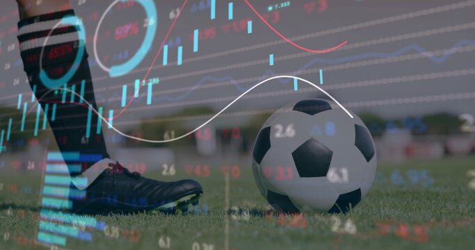 Placing player with striped knee socks and cleats beside soccer ball on grass pitch, market charts