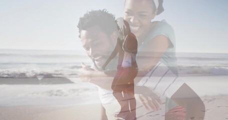 Playing couple giving piggyback and smiling on beach, wearing light shorts, translucent silhouette
