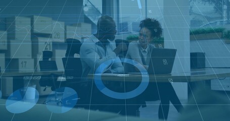 Discussing two coworkers wearing blazers reviewing laptop at meeting table, boxes and data overlay