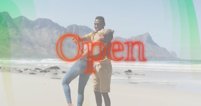 Holding couple hugging on sandy beach, both wearing casual clothes, red Open graphic overlay - Powered by Adobe
