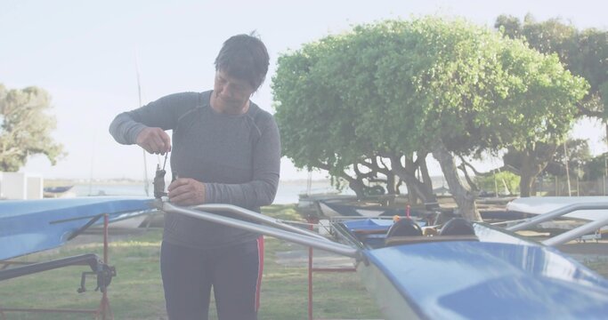 Working woman fixing rigging on blue shell at boatyard wearing gray top red leggings holding wrench