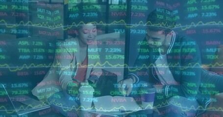 Reviewing two colleagues in blazers checking tablet, documents at office nook with laptop, tickers