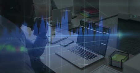 Reviewing coworkers in button-down and blouse analyzing charts at office table, with central laptop