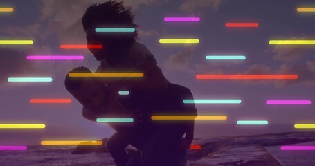 Giving man carrying woman piggyback in casual outerwear on beach at sunset, neon bars streaking