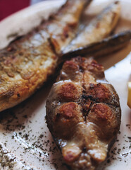 Montenegrin cuisine, fish assortment platter, fried grilled crucian carp steak, roasted pastrmka and bleak on plate with lemon and salad served in a restaurant in Montenegro, Skadar lake, Virpazar