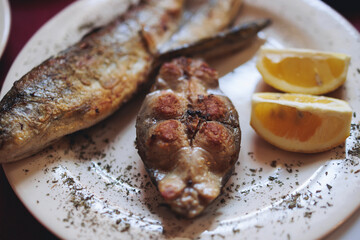 Montenegrin cuisine, fish assortment platter, fried grilled crucian carp steak, roasted pastrmka and bleak on plate with lemon and salad served in a restaurant in Montenegro, Skadar lake, Virpazar