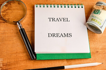 A travel journal with bold text sits open on a wooden surface, accompanied by a magnifying glass...