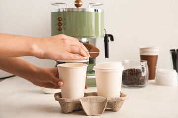 Woman with takeaway cups of tasty coffee on white background