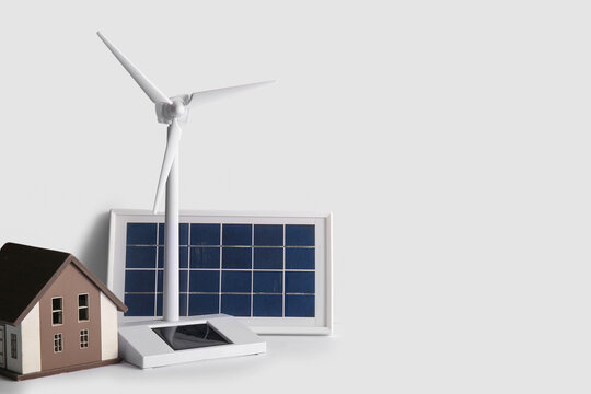 Wind turbine, house model and solar panel on white background
