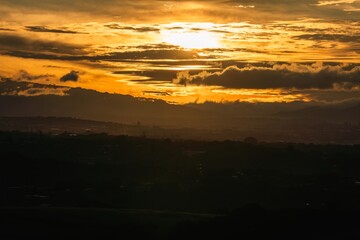 Obraz premium Beautiful sunrise over the hills highlights the sky with vibrant orange and yellow colors in the early morning