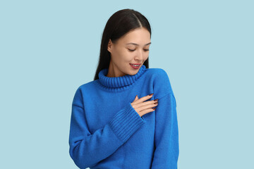 Beautiful young woman in blue knitted sweater on light background