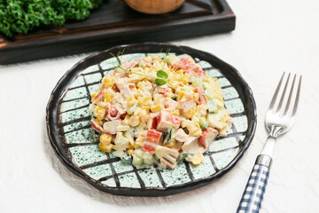 Plate of salad with crab sticks, corn and cucumber on white background