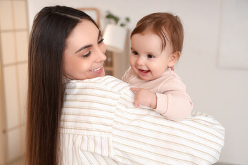Happy young mother holding her baby at home, closeup