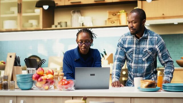 Black young couple starting a duel with kitchen utensils for the game, playful fight with fake swords during the goofy war. Childish silly adversaries having fun together in the morning. Camera B.