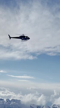 LOW ANGLE VIEW: Heliskiing helicopter flies over picturesque snowy mountain tops. Flight transport for adventurous freeride heliboarding in breath-taking and untouched mountains of spectacular Albania